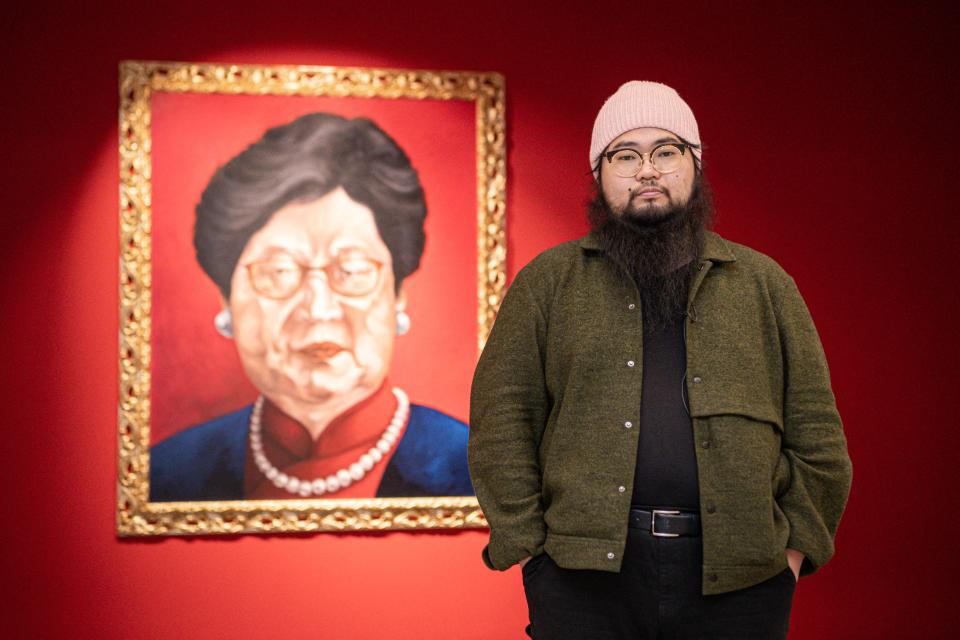 Chinese dissident artist Badiucao poses next to his artwork entitled 