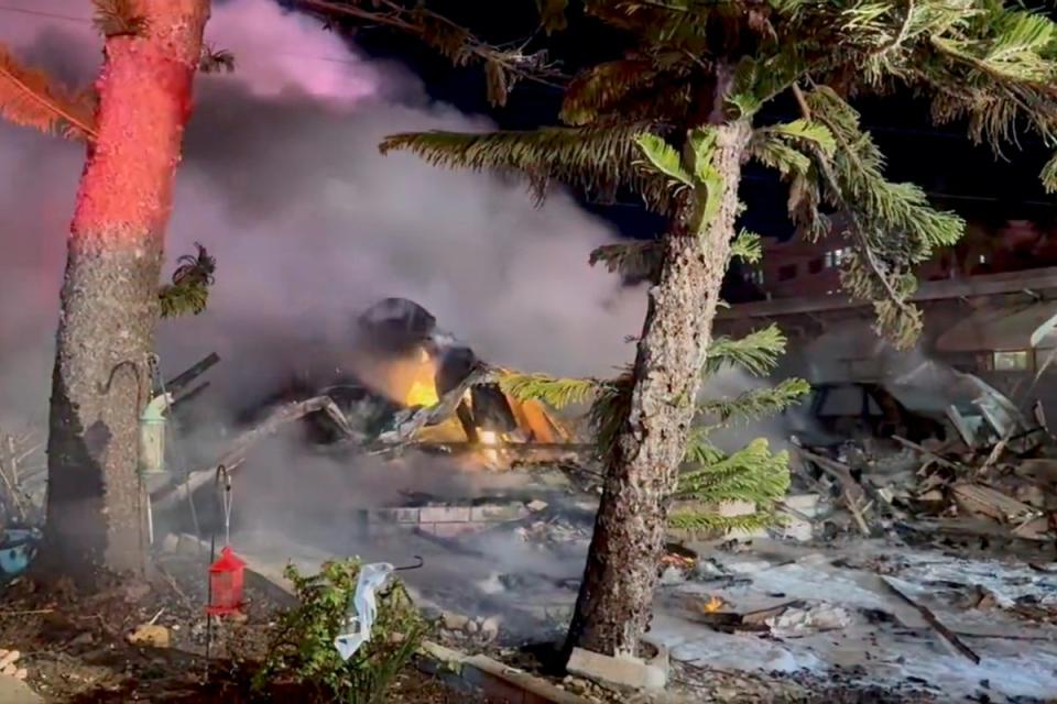 Smoke pours from the wreckage site after a small plane crashed into and demolished a mobile home (via REUTERS)