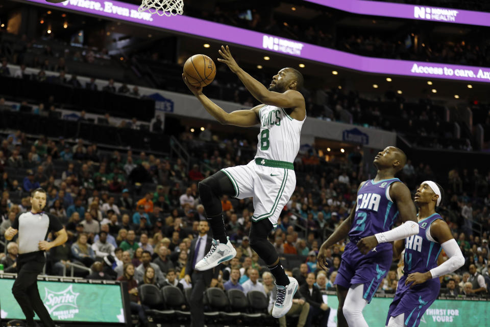 Boston Celtics' Kemba Walker (8) slips by for an easy two as Charlotte Hornets' Terry Rozier (3) and Devonte' Graham (4) trail in the paint during the first half of an NBA basketball game in Charlotte, N.C., Tuesday, Dec. 31, 2019. (AP Photo/Bob Leverone)