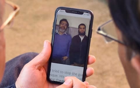 Relatives look the pictures of Pakistani citizen Rashid Naeem, and his son Talha Naeem - Credit: AP