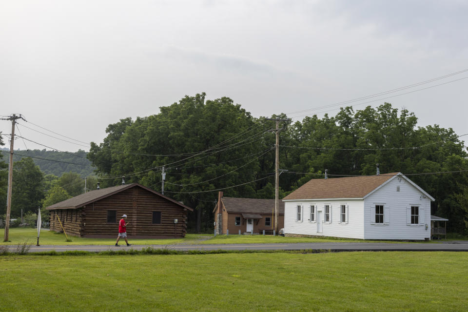 A man walks outside the Onondaga Nation's longhouse, where meetings and ceremonies are held, Thursday, Aug. 3, 2023, on the Onondaga Nation Territory in central New York. The Nation's territory once stretched more than 2 million acres. The present-day territory, just south of Syracuse, is approximately 7,300 acres. (AP Photo/Lauren Petracca)