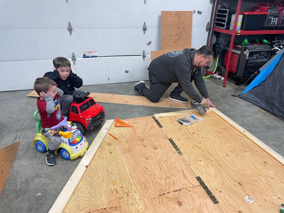 Dax Babcock (left) and his brother Colton hold their ears while dad Michael Babcock works on a project