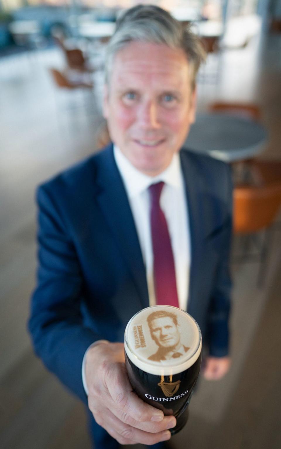 Sir Keir Starmer holds a pint of Guinness with his face on during a visit to Dublin today - Stefan Rousseau/PA