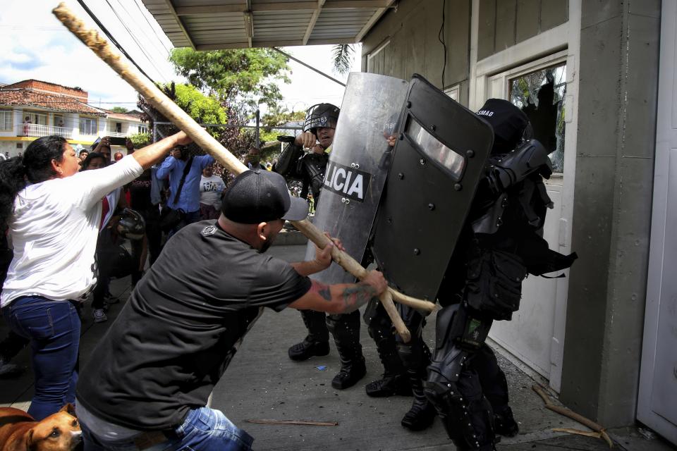 Inmates' relatives clash with police at the entrance of a prison where there was a deadly fire in Tulua, Colombia, Tuesday, June 28, 2022. Authorities say at least 51 people were killed after the fire broke out during what appeared to be an attempted riot early Tuesday. (AP Photo/Andres Quintero)