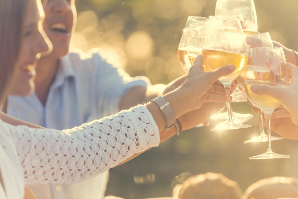 A group of friends having drinks and celebrating at sunset with a wine toast. (Photo via Getty Images)