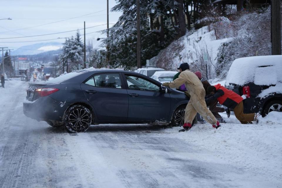 A group of sledders helped push a car out of the snow after it got stuck on N State Street on January 17, 2024, in Bellingham, Wash.