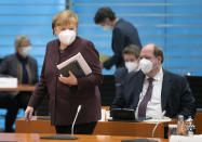 FILE - In this file photo dated Wednesday, Feb. 10, 2021, German Chancellor Angela Merkel, front left, walks past Helge Braun, Head of the Chancellery, right, as she arrives for the weekly cabinet meeting in Berlin, Germany. Slow off the blocks in the race to immunize its citizens against COVID-19, Germany faces the problem of having a glut of vaccines and not enough arms to inject. With its national vaccine campaign lagging far behind that of Israel, Britain and the United States, there are growing calls in this country of 83 million to ditch or rewrite the rulebook. (AP Photo/Michael Sohn, FILE)