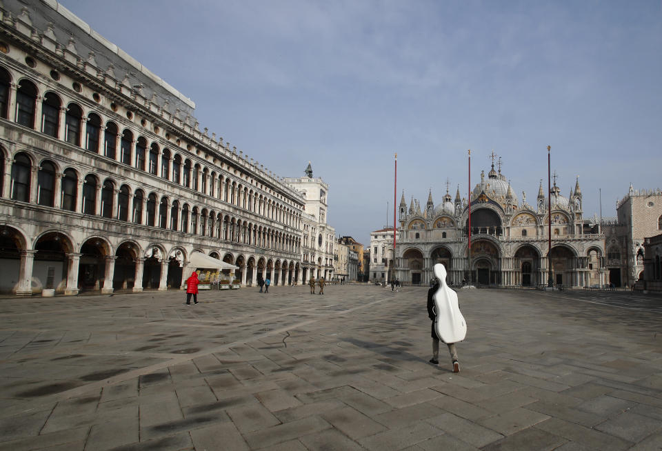 A young man walks in an empty St. Mark's Square in Venice, Italy, Saturday, Jan. 30, 2021. Gondolas and other vessels are moored instead of preparing for Carnival's popular boat parade in the lagoon. Alleys are eerily empty. Venetians and the city's few visitors stroll must be masked in public places, indoors and out, under a nationwide mandate. (AP Photo/Antonio Calanni)