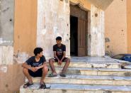 Sharfeddine al-Shahomi, 17, sits on the steps of his apartment building in the 600 Block district of Libya’s Sirte that was damaged in fighting