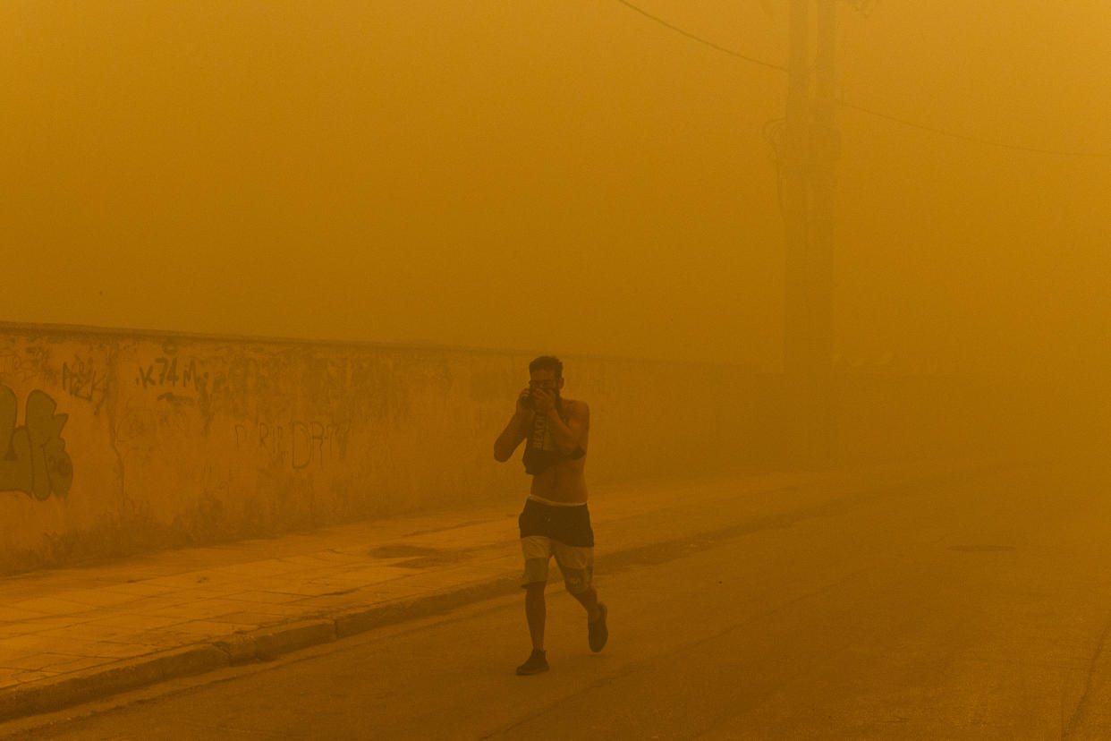 With his upper body bare and a cloth over his mouth, a man walks through Penteli, a municipality in the northern Athens region, on Monday.