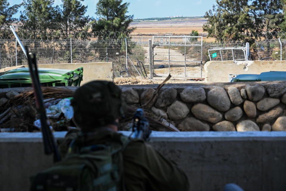 An Israeli soldier guards the broken fence that Hamas militants crashed through to enter the Kfar Aza kibbutz days earlier, near the border with Gaza, Oct. 15, 2023 in Kfar Aza, Israel. / Credit: Alexi Rosenfeld/Getty