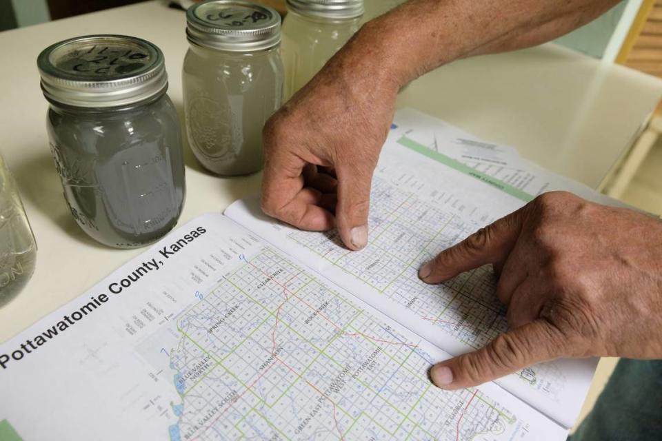 Rodney Biesenthal points to a map of townships in Pottawatomie County. In the background are water samples he has collected.