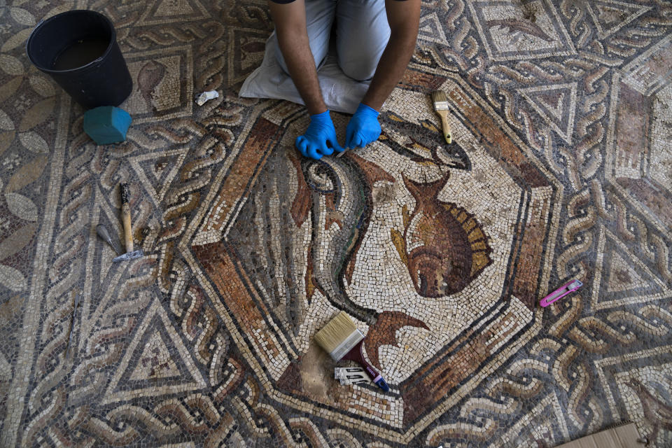 A worker cleans a restored Roman-era mosaic ahead of its display in its hometown ahead of the inauguration of the Shelby White & Leon Levy Lod Mosaic Archaeological Center, in Lod, central Israel, Thursday, June 23, 2022. A series of well-preserved ancient Roman mosaics have returned home to the central Israel city of Lod after more than a decade touring the world's most prominent museums. Israel on Monday inaugurated a new museum to house the artworks that once adorned a Roman-era villa. (AP Photo/Oded Balilty)