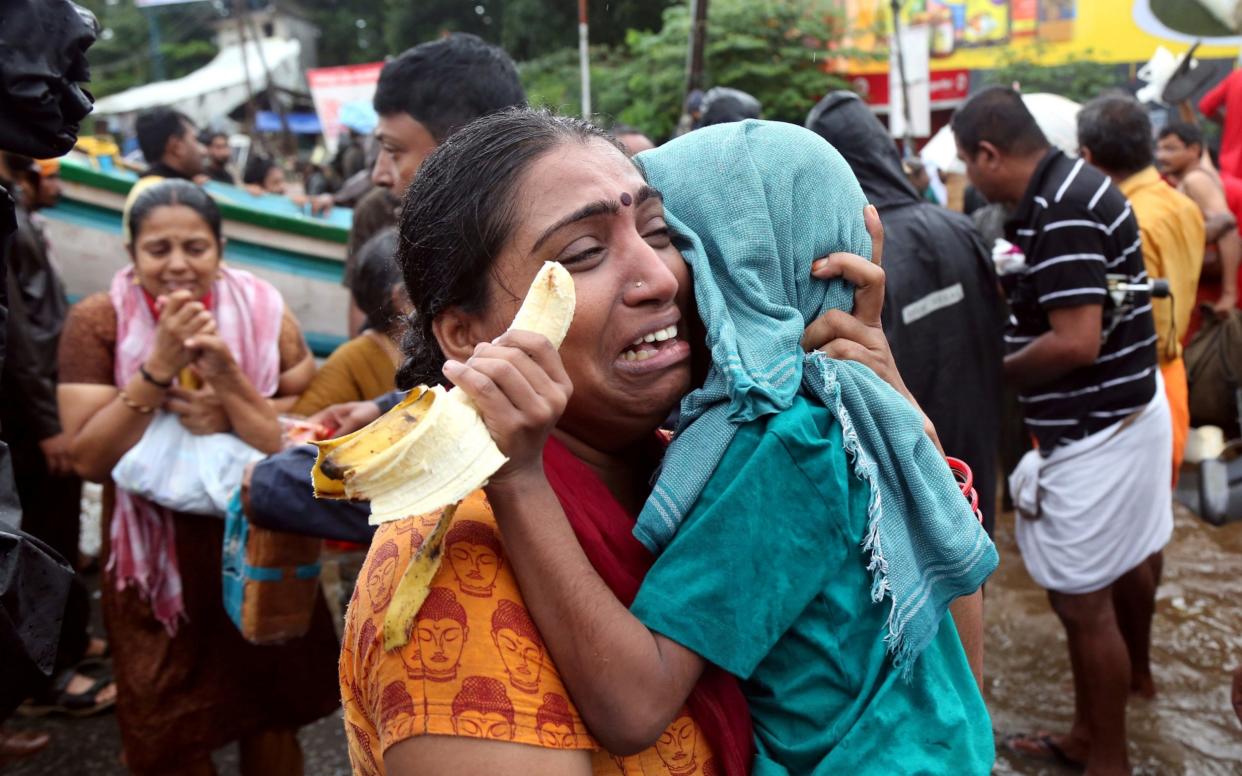 A woman cries as she holds her son after they were evacuated from a flooded area in Aluva - REUTERS