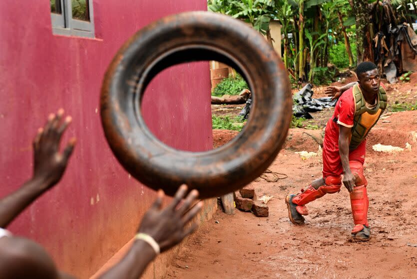 Dennis Kasumba throws an old tire to build strength outside his home in Guyaza, Uganda.