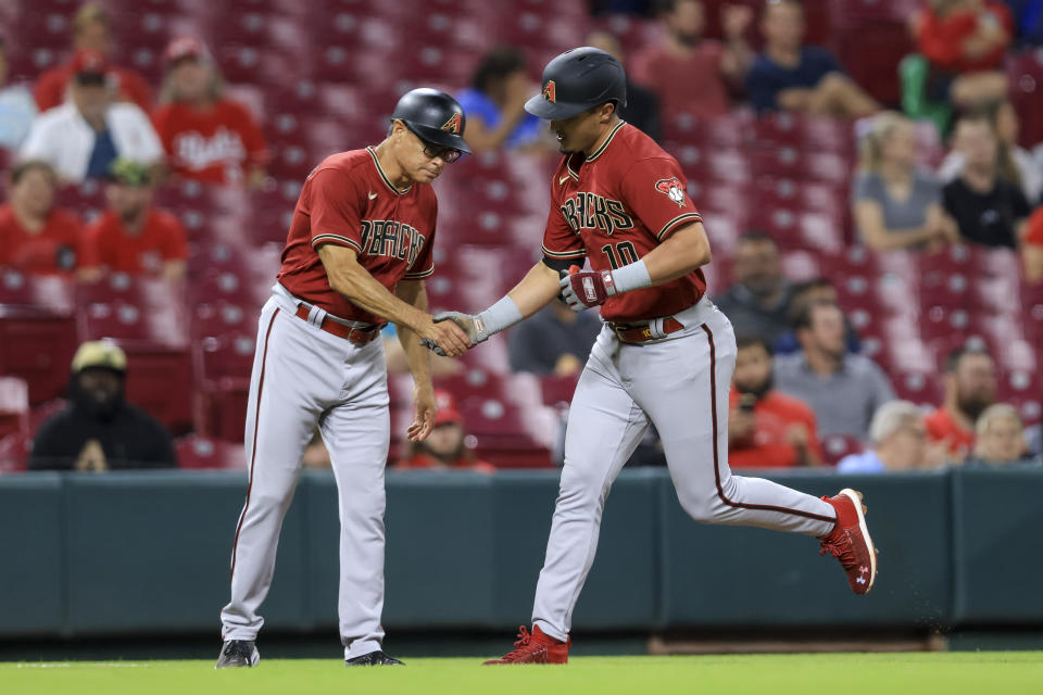 Arizona Diamondbacks' Josh Rojas, right, shakes hands with third base coach Tony Perezchica after hitting a solo home run during the fifth inning of the team's baseball game against the Cincinnati Reds in Cincinnati, Wednesday, June 8, 2022. (AP Photo/Aaron Doster)
