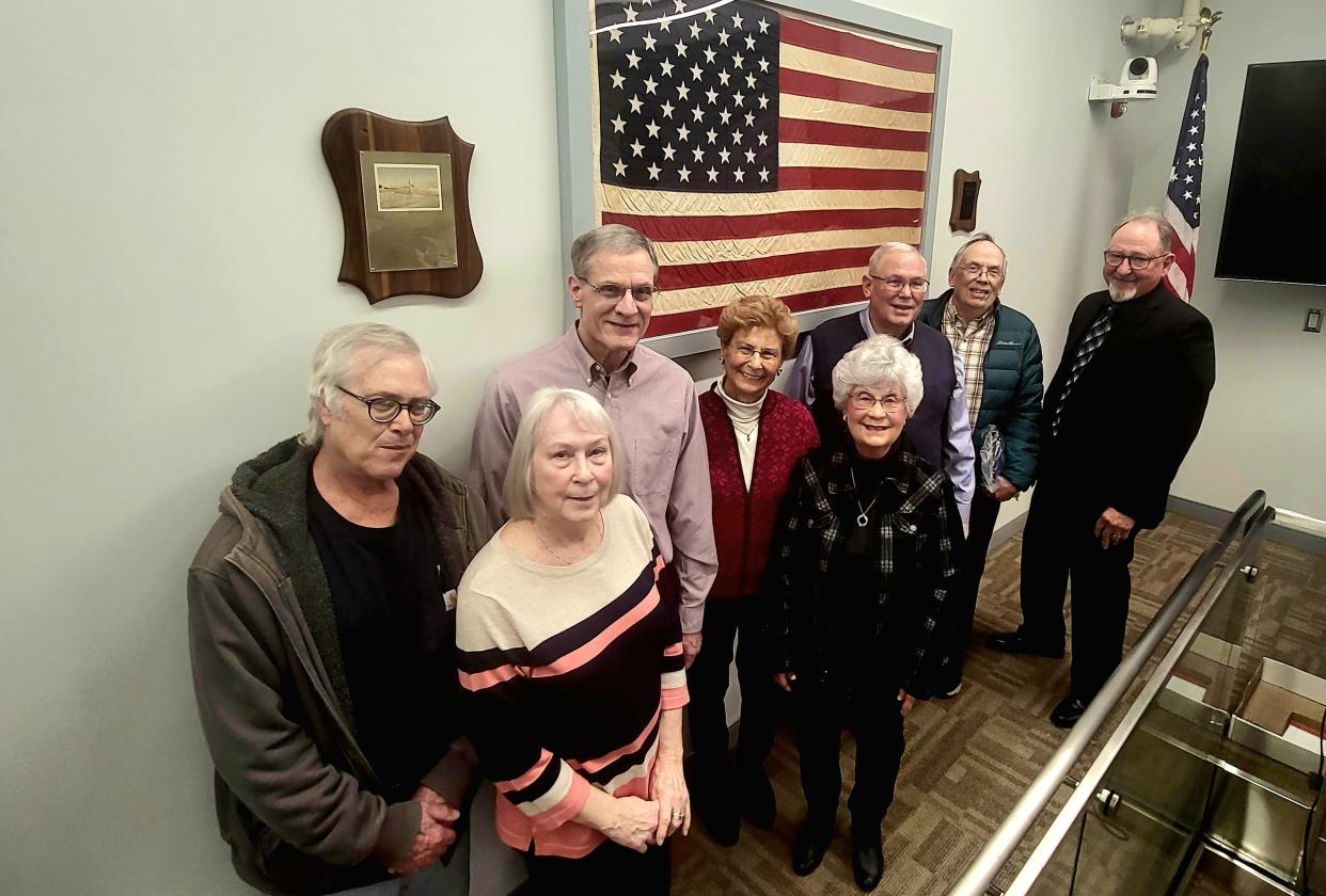 Marysville native Gary Brougham and Councilman David Barber, far right, and members of the Dream City Preservation Group stand near a flag Brougham once brought back from the South Pole on Monday, March 25, 2024. The flag, previously dedicated to the city in 1972, was unveiled newly on display during Monday's regular City Council meeting.