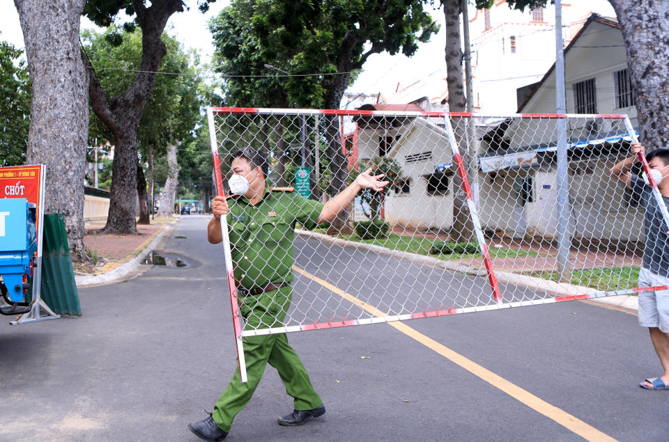 Police officers remove a barricade in Vung Tau, Vietnam Thursday, Sept. 30, 2021. Vietnam will lift a lockdown order in its largest city on Friday, ending almost three months of strict movement restrictions to curb a coronavirus surge. (AP Photo/Hau Dinh)