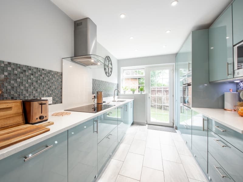 A general interior view of a new small green galley kitchen with glossy cabinets