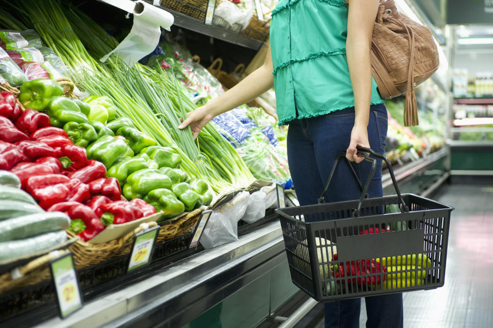 A woman with a shopping basket chooses vegetables in a supermarket as inflation rises.
