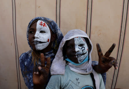 Sudanese girls with half painted faces make victory signs as they watch the protesters demonstrating outside the defense ministry compound in Khartoum, Sudan, April 25, 2019. REUTERS/Umit Bektas