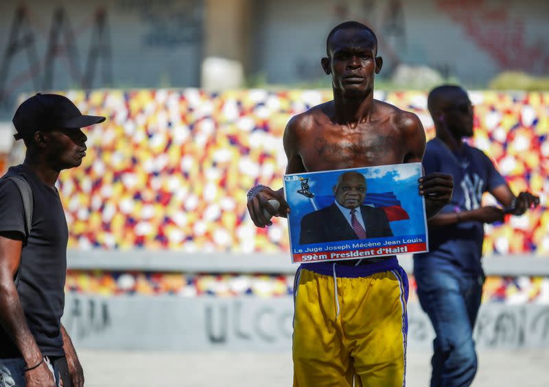 A man holds a photograph of Supreme Court Judge Joseph Mecene Jean-Louis during protests against Haiti's President Jovenel Moise, in Port-au-Prince