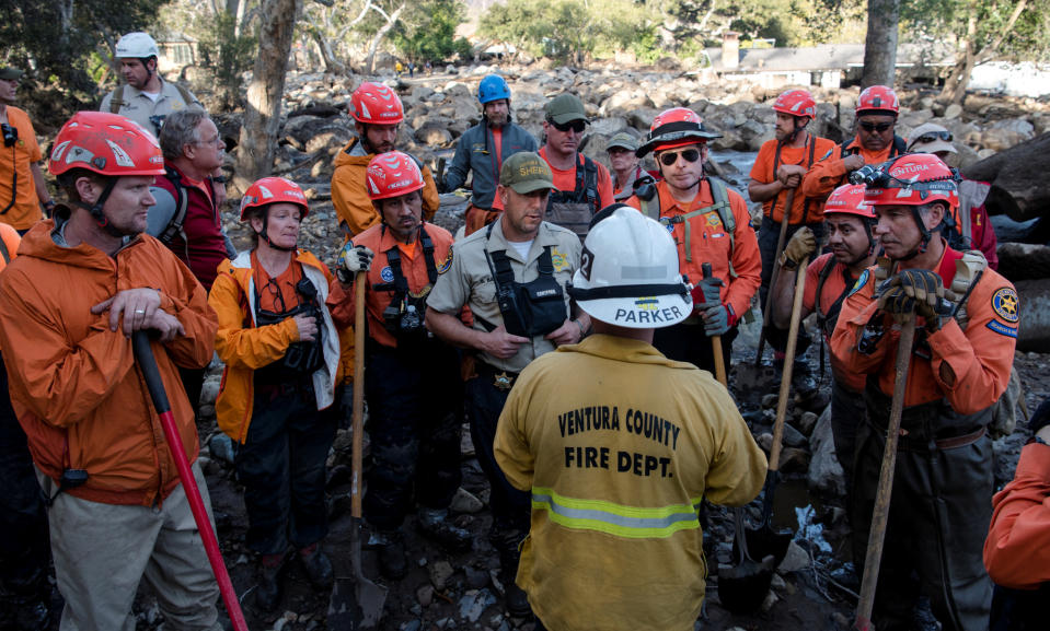 <p>Ventura Search & Rescue volunteers (in orange) listen to a briefing from a Ventura County firefighter on Glen Oaks Road in Montecito, Calif., Jan. 10, 2018. (Photo: Kenneth Song/Santa Barbara News-Press via Reuters) </p>