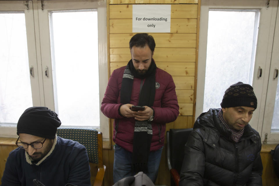 In this Jan. 30, 2020, photo, a Kashmiri journalist, center, browses the internet on his mobile phone inside the media center set up by government authorities in Srinagar, Indian controlled Kashmir. Six months after India stripped restive Kashmir of its semi-autonomy, enforcing a total communications blackout, it has restored limited internet at slow speeds with access only to government-approved websites. Since Modi came into power in 2014, the internet has been suspended more than 365 times in India, according to the global digital rights group Access Now. (AP Photo/ Dar Yasin)