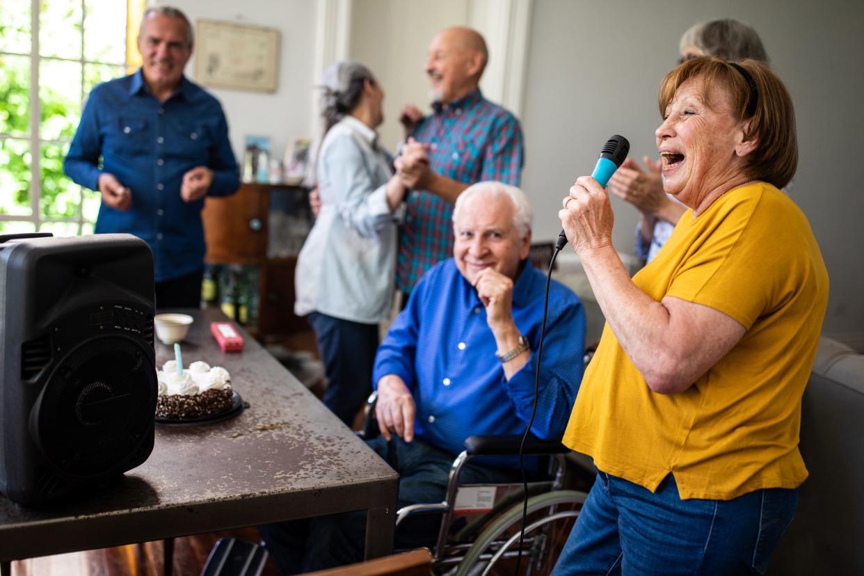 Group of Senior people having fun at Karaoke party, celebrating birthday in dining room at home