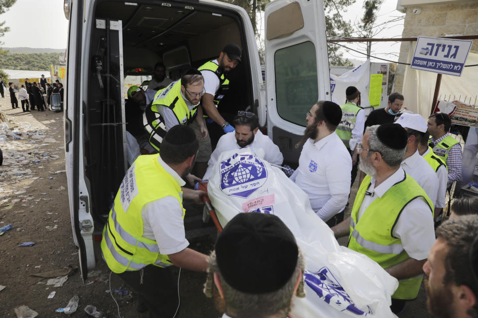 FILE - In this April 30, 2021 file photo, Israeli security officials and rescuers carry a body of a victim who died during a Lag Baomer celebrations, at Mt. Meron in northern Israel. An Israeli government commission investigating the deadly accident held its first day of hearings Sunday, Aug. 22, 2021, almost four months after the stampede at Mount Meron left 45 people dead. The April 29 incident was the deadliest civilian disaster in the country's history. (AP Photo/Sebastian Scheiner, File)