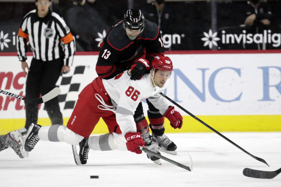 Carolina Hurricanes' Warren Foegele (13) hits Detroit Red Wings' Mathias Brome (86) as they go for the puck during the first period of an NHL hockey game in Raleigh, N.C., on Thursday, March 4, 2021. (AP Photo/Chris Seward)