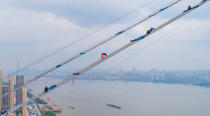 <p>This photo taken on May 8, 2018 with a drone shows workers labouring on the construction of a double-deck suspension bridge crossing the Yangtze River in Wuhan in China’s central Hubei province. (Photo from AFP/Getty Images) </p>