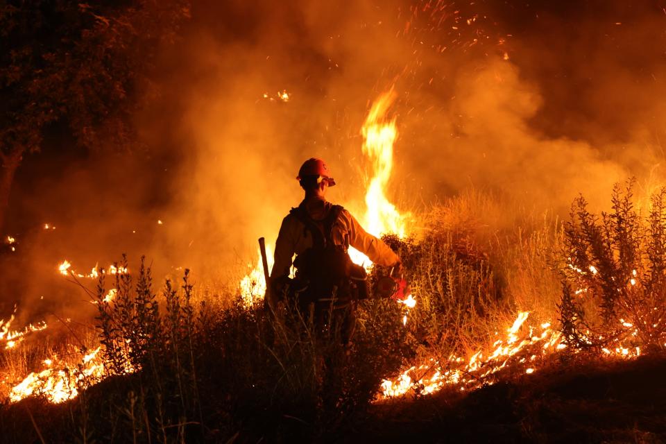 A firefighter monitors and sets a controlled burn as the Rabbit Fire scorched over 7,500 acres in Moreno Valley, Riverside County, Calif. on July 15, 2023.