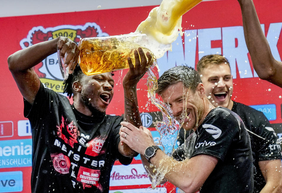 Leverkusen's head coach Xabi Alonso , centre, is sprayed with beer after Bayer Leverkusen won the German Bundesliga title beating Werder Bremen in Leverkusen, Germany, Sunday, April 14, 2024. (AP Photo/Martin Meissner)