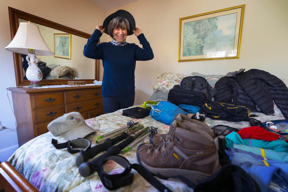 Cindy Charest tries on her sun hat while arranging her hiking gear at her home, Wednesday, March 17, 2021, in Westbrook, Maine. The avid traveler is looking forward to resuming her travels now that she and her husband have been vaccinated for COVID-19. Spring has arrived, and many older adults who have been vaccinated are emerging from hibernation imposed by the coronavirus pandemic. (AP Photo/Robert F. Bukaty)