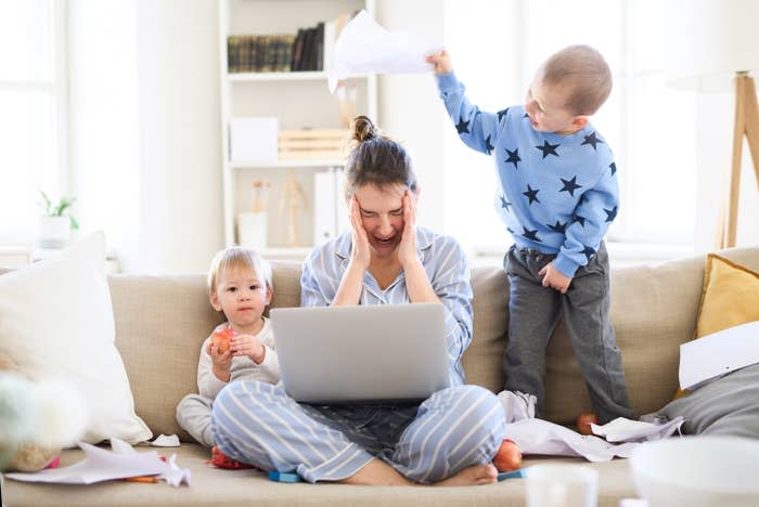 mom trying to work while toddles play on the couch next to her