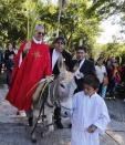 Father Jose Kentenich holds palm fronds as he rides a donkey during a Palm Sunday celebration outside the Our Lady of Schoenstatt Sanctuary in Ypacarai, April 13, 2014. Palm Sunday commemorates Jesus Christ's triumphant entry into Jerusalem on the back of a donkey. REUTERS/Jorge Adorno (PARAGUAY - Tags: RELIGION)