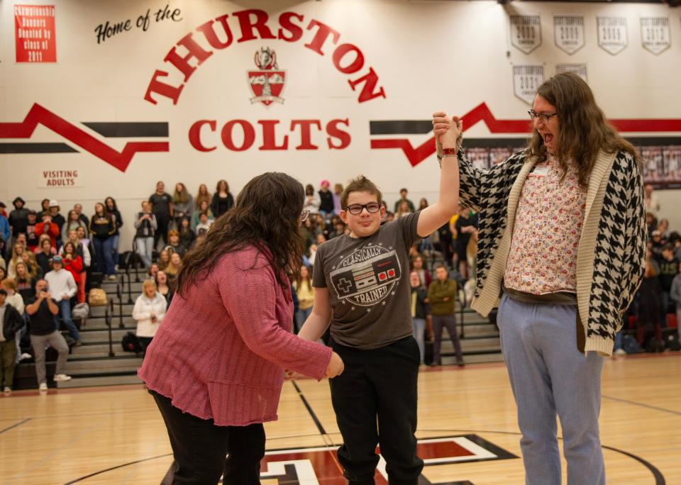 Sam Lockard, center, celebrates with his mother Jennifer Clason, left, and friend Alex Bruce during a school assembly at Thurston High School where he was introduced as the first “sparrow” for the new club.