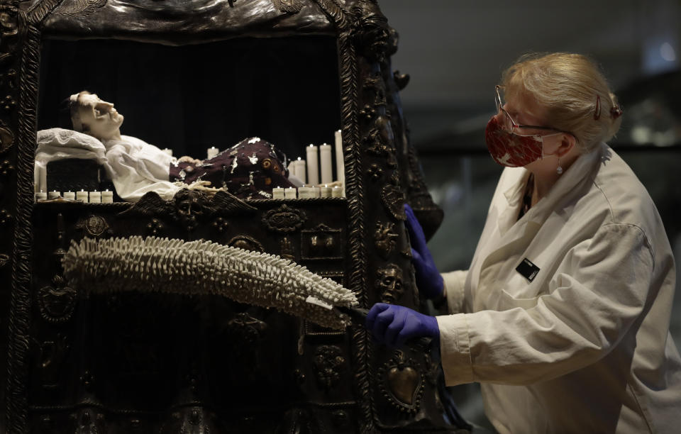 Kate Perks, Senior Collections Care Conservator cleans a sculpture by Eleanor Crook called Santa Medicina, which combines medical and religious symbolism to help us reflect on the frailty of human life, displayed in Medicine: The Wellcome Galleries, at the Science Museum in London, Monday, May 17, 2021. The Science Museurm reopens to the public on Wednesday. (AP Photo/Kirsty Wigglesworth)