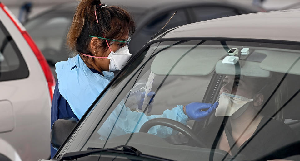 A health worker testing a person in a drive-through Covid-19 testing clinic.