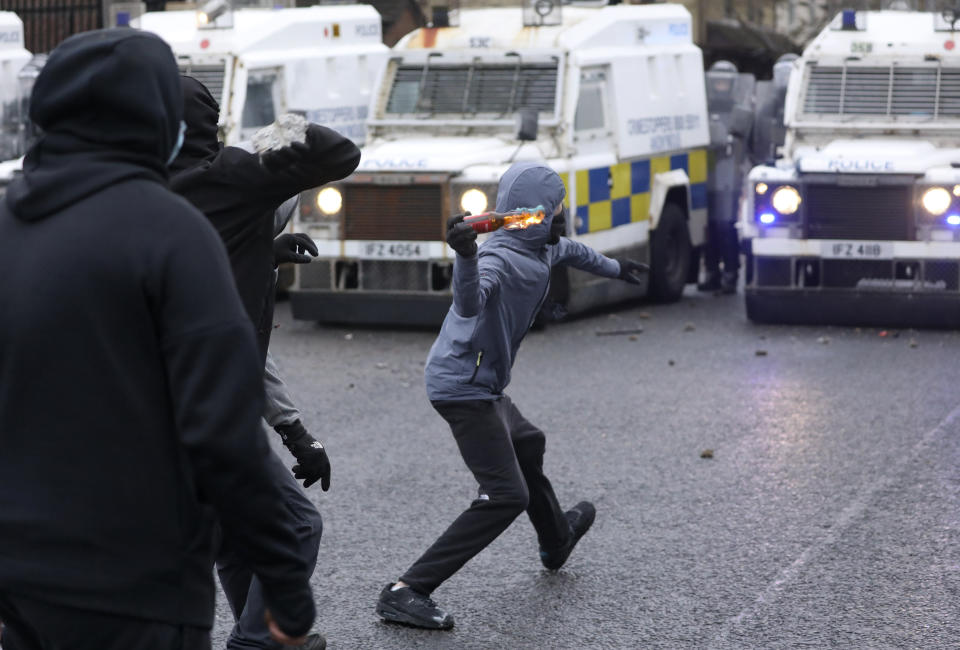 A Nationalist youth throws a projectile at a police line blocking a road near the Peace Wall in West Belfast, Northern Ireland, Thursday, April 8, 2021. Authorities in Northern Ireland sought to restore calm Thursday after Protestant and Catholic youths in Belfast hurled bricks, fireworks and gasoline bombs at police and each other. It was the worst mayhem in a week of street violence in the region, where Britain's exit from the European Union has unsettled an uneasy political balance. (AP Photo/Peter Morrison)
