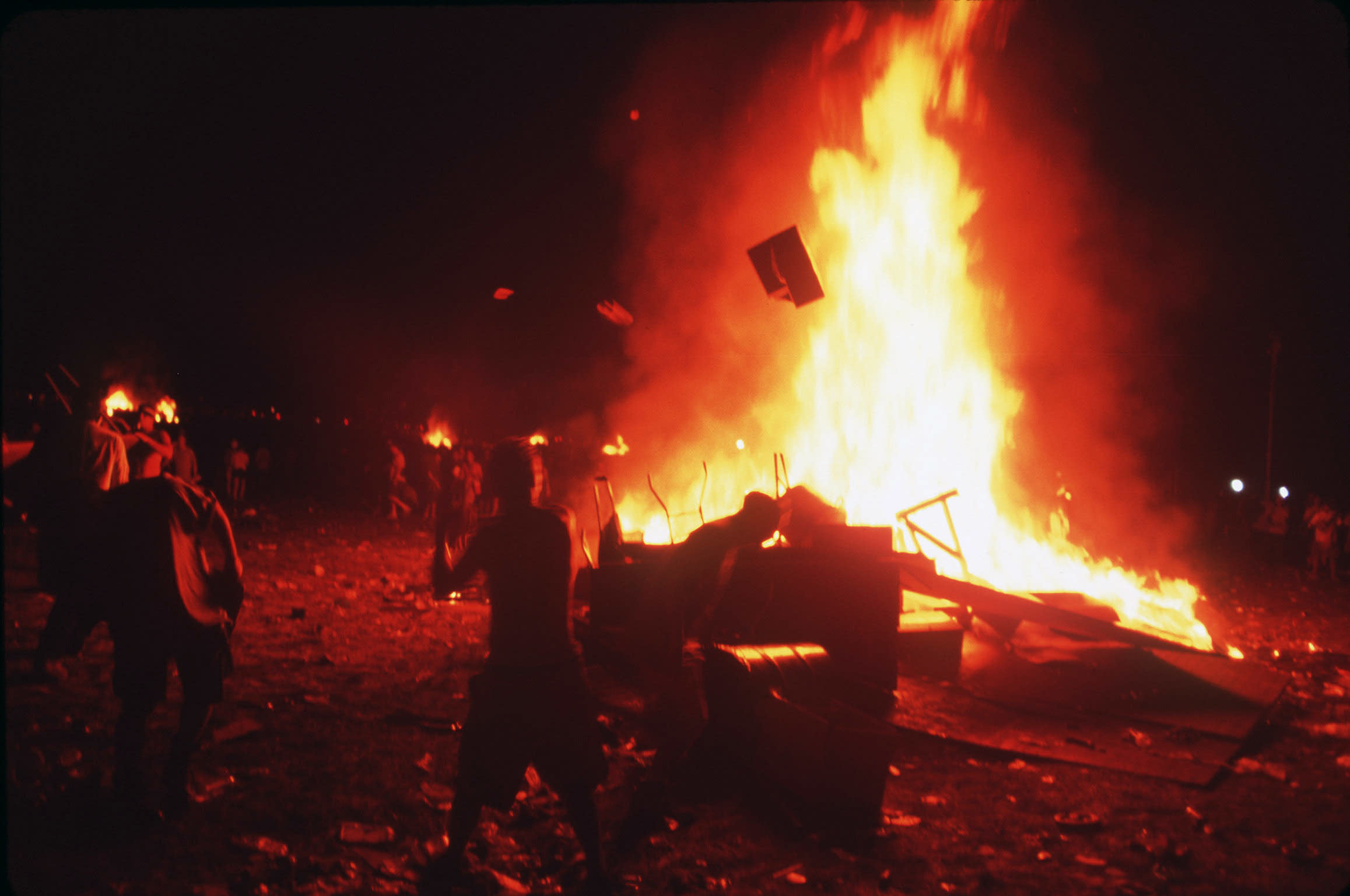 Huge fires are raging as people gather around them.