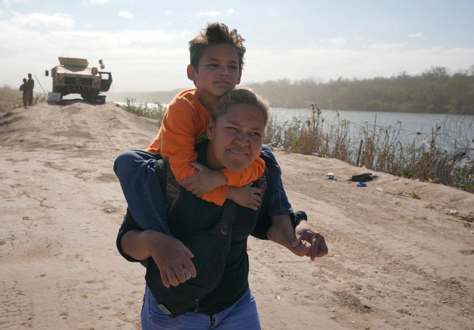 Rosa Diaz walks along the banks of the Rio Grande with her 6-year-old son, Fabian Los Diaz, to surrender Monday to the U.S. Border Patrol after they crossed the border at Eagle Pass with a group of fellow migrants from Venezuela.