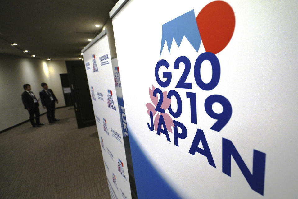 FILE - In this June 7, 2019, file photo, staff members stand near the emblem of G20 2019 Japan at the entrance of the press center of G20 Finance Ministers' and Central Bank Governors' Meeting in Fukuoka, western Japan. Chinese and U.S. trade negotiators are in contact on ways of resolving disputes ahead of an expected meeting between their heads of state at the G-20 summit in Japan later this week, a Chinese official said Monday, June 24, 2019. (AP Photo/Eugene Hoshiko, File)