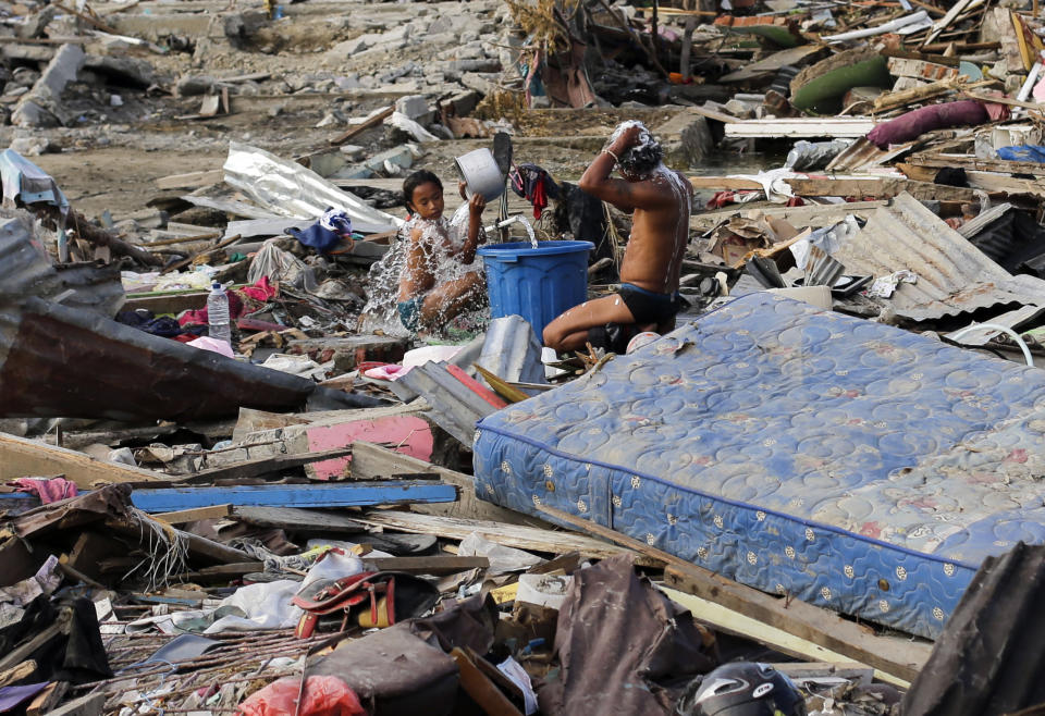 In this Friday, Oct. 5, 2018, file photo, residents take a bath surrounded by toppled homes and structures at the earthquake and tsunami-hit Palu, Central Sulawesi, Indonesia. (AP Photo/Aaron Favila, File)