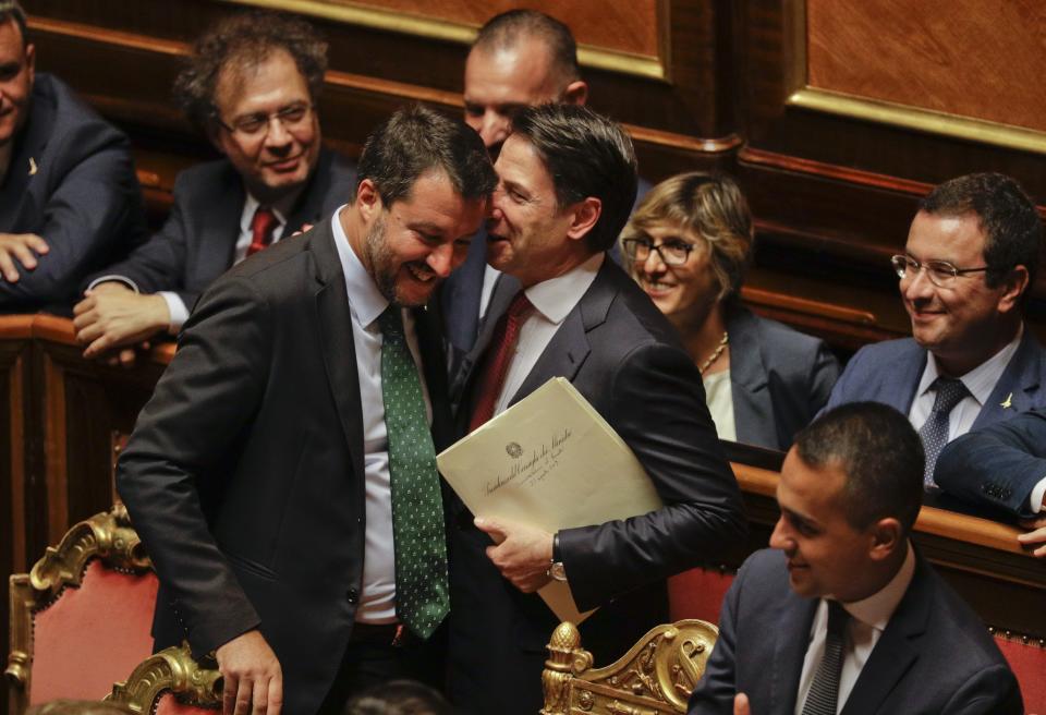 Italian Premier Giuseppe Conte, right, shares a word with Deputy-Premier Matteo Salvini before addressing the Senate in Rome, Tuesday, Aug. 20, 2019. The political showdown on Tuesday was triggered two weeks ago by hard-line Interior Minister Matteo Salvini, known across Europe for his tough stance against migrants, when he pulled the plug on the shaky populist coalition forged only 14 months earlier between his right-wing League and the anti-establishment 5-Star Movement. (AP Photo/Gregorio Borgia)