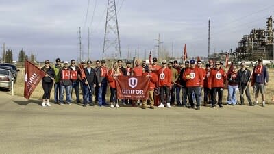 Large group of members posing in a group outside holding up a Unifor flag. (CNW Group/Unifor)