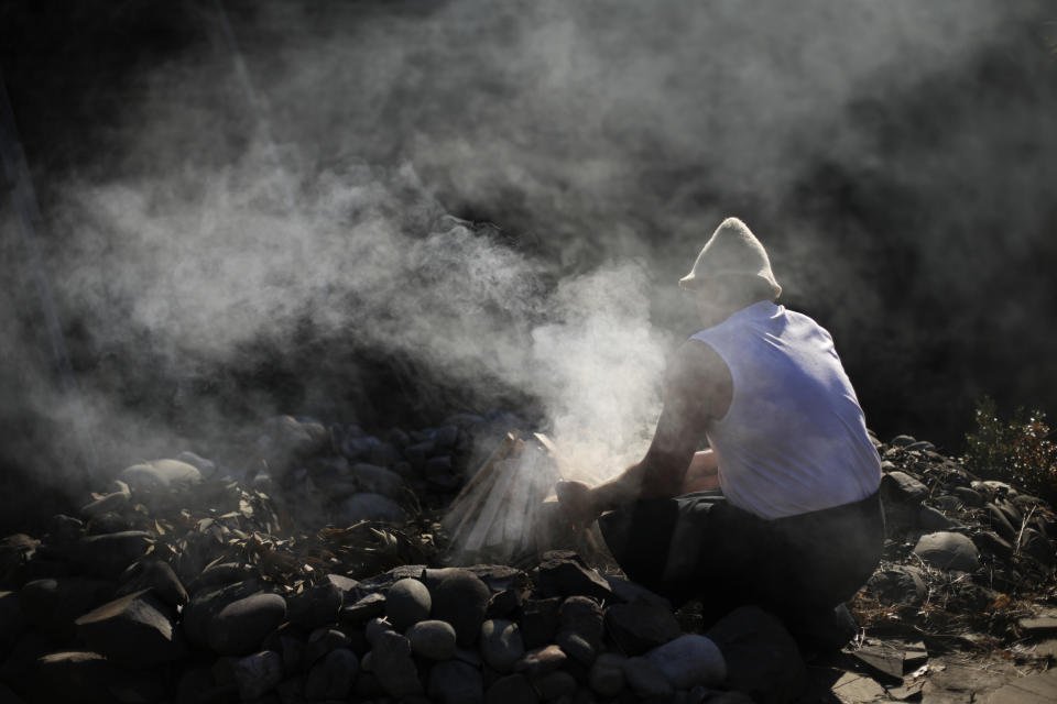 Bathhouse master Ivan Tkach starts a fire to heat up the stones for a sweat lodge at the British Banya bathhouse, Saturday, Feb. 15, 2014, in Krasnaya Polyana, Russia. "The most important thing about the banya is to have a good spirit in the body," Tkach says. (AP Photo/Jae C. Hong)