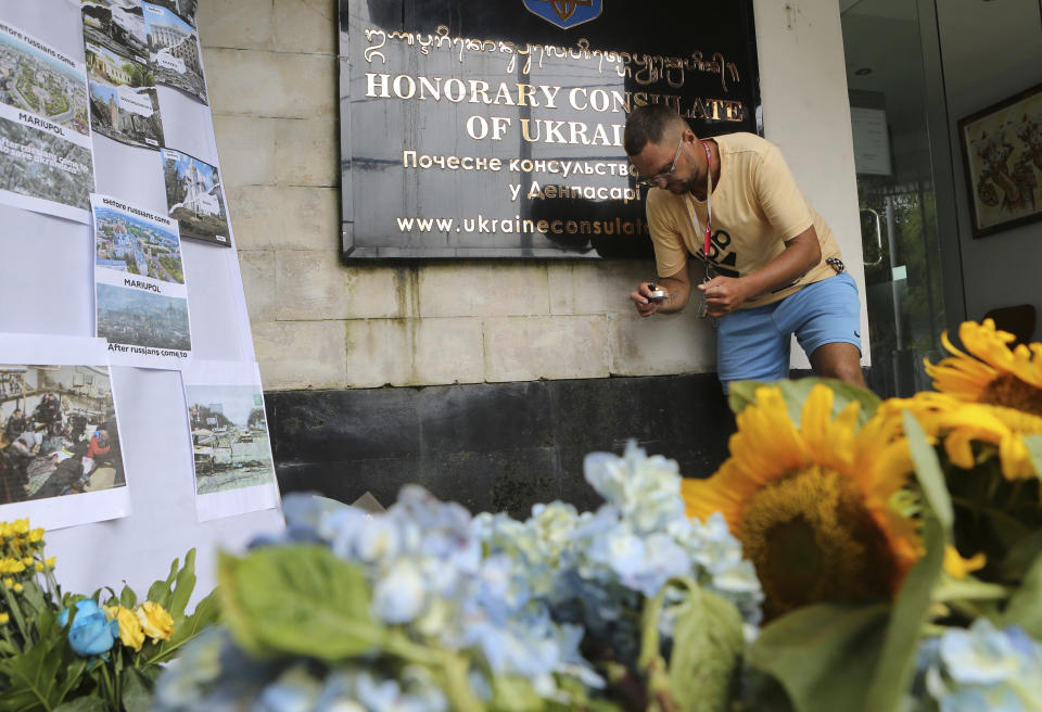 A Ukrainian national lights a candle to pay tribute to people killed in Russia's war against Ukraine to mark the one-year anniversary of Russia's invasion of Ukraine, at Ukraine consulate in Bali, Indonesia on Friday, Feb. 24, 2023. (AP Photo/Firdia Lisnawati)