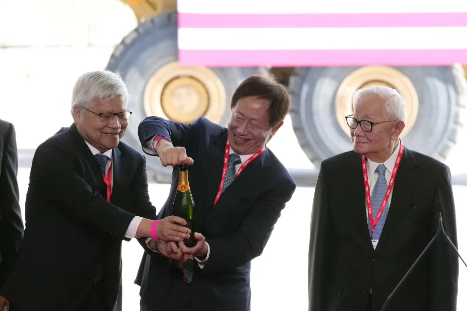 Taiwan Semiconductor Manufacturing Company Chairman Mark Liu, middle, and CEO C.C. Wei, left, open a bottle of champagne as TSMC founder Morris Chang, right, looks on at their new facility in Phoenix, Tuesday, Dec. 6, 2022. (AP Photo/Ross D. Franklin)